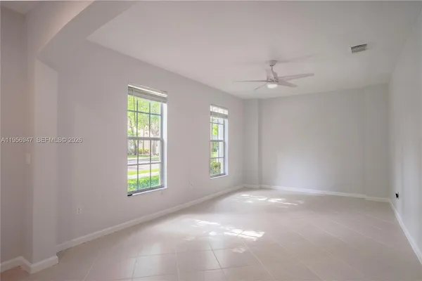 an empty room with windows and chandelier fan