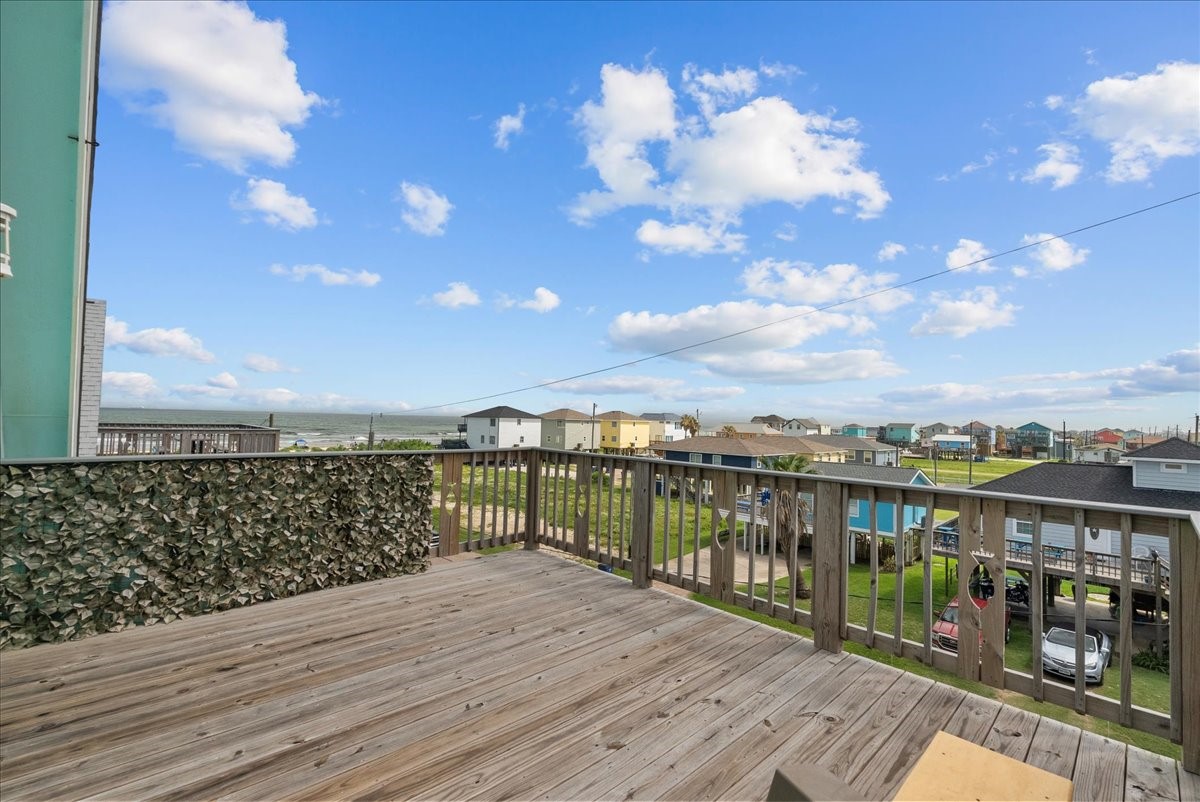 130 Beachcomber Avenue Surfside Beach, TX 77541 - Photo 24 of 33 This photo showcases a spacious wooden deck with a clear view of a neighborhood and distant horizon, perfect for outdoor relaxation and enjoying scenic surroundings.