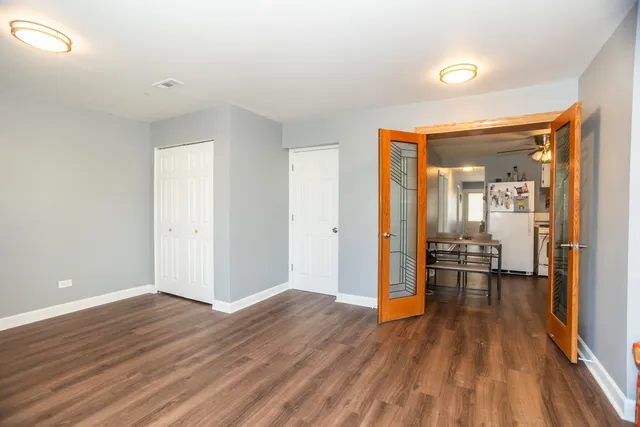 an empty room with wooden floor fan and windows