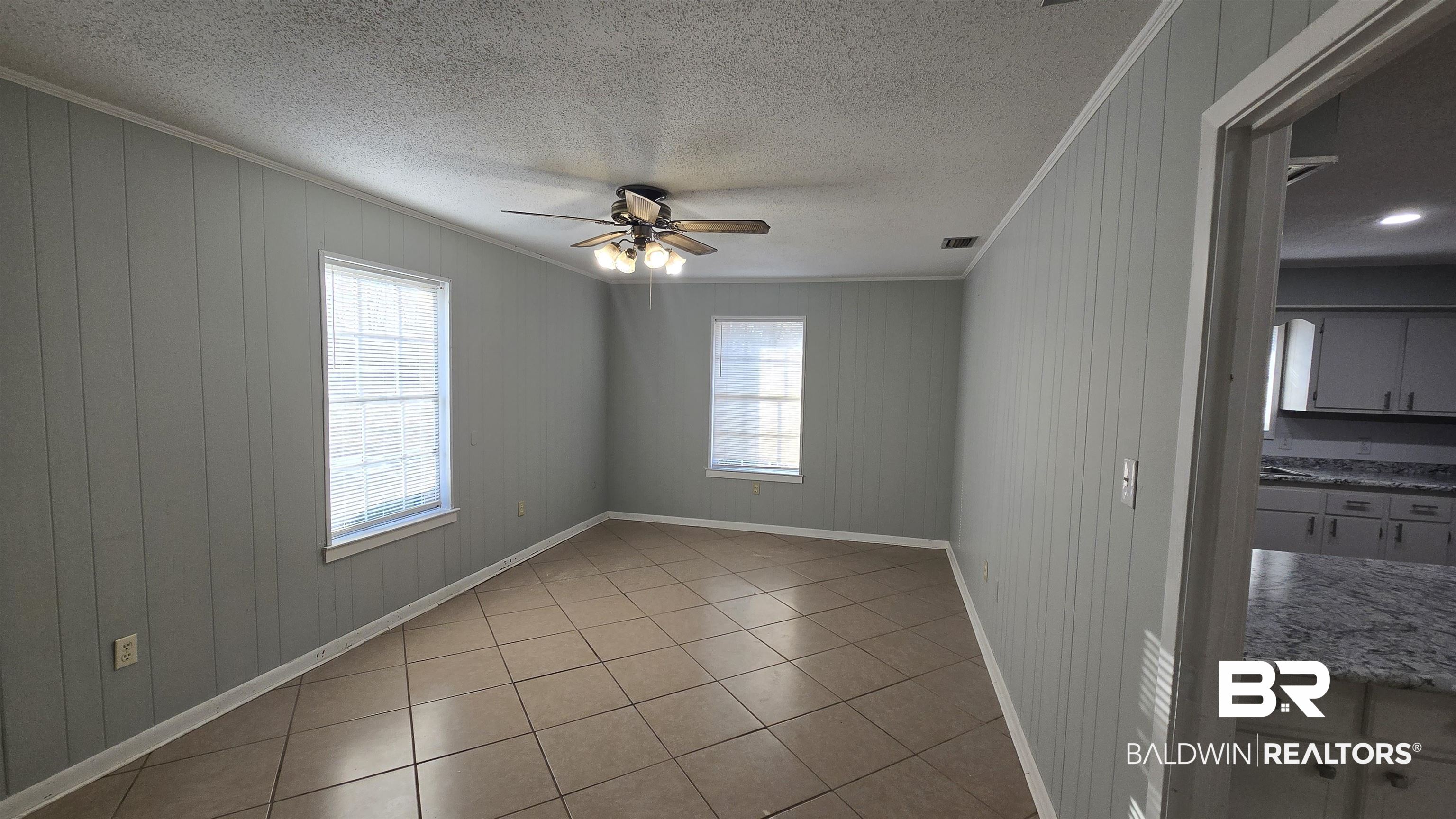 615 East Pedigo Avenue Foley, AL 36535 - Photo 23 of 31 Unfurnished room featuring a textured ceiling, a ceiling fan, light tile patterned floors, ornamental molding, and wooden walls