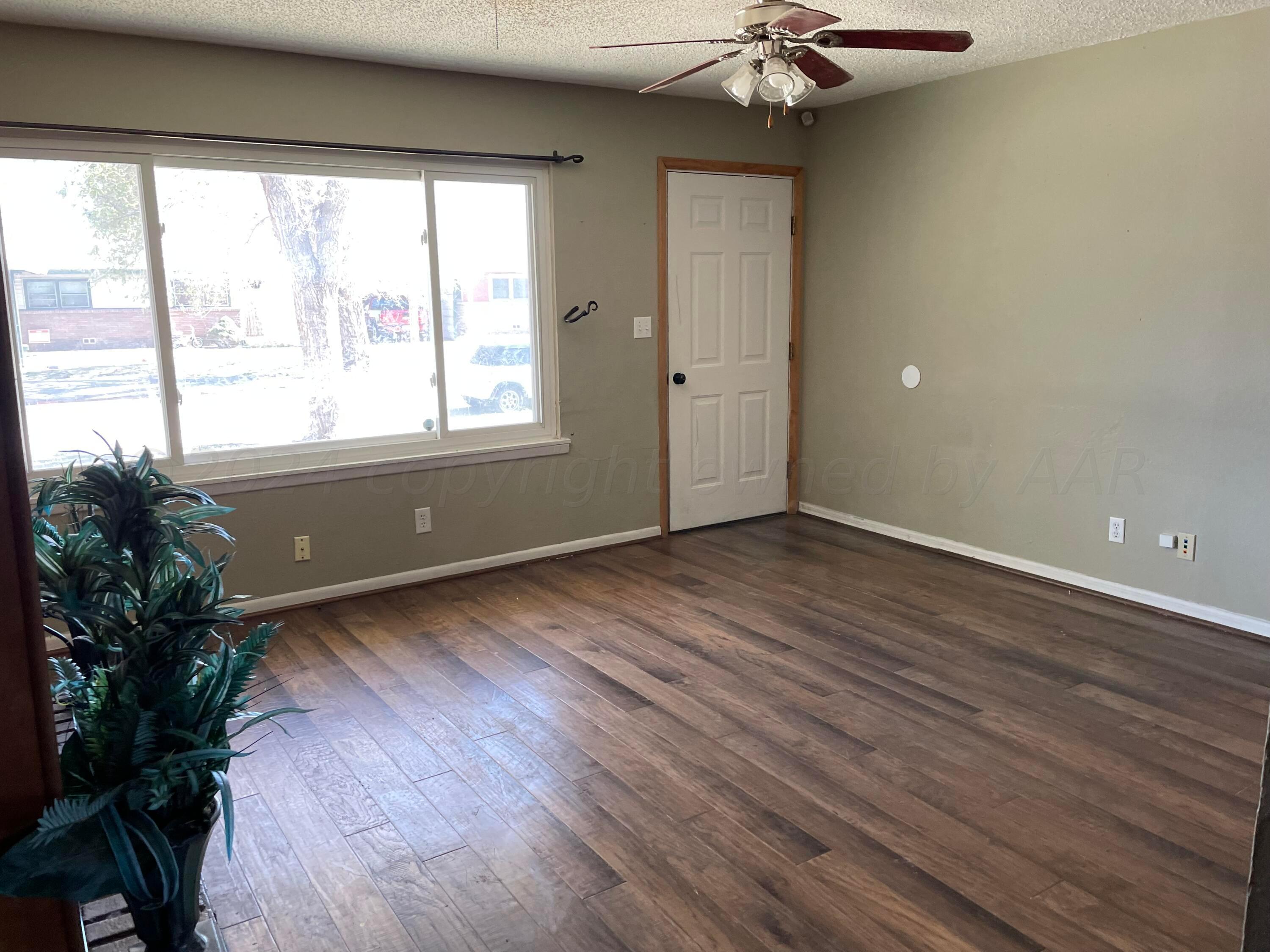 2014 South Drake Street Perryton, TX 79070 - Photo 3 of 10 a view of an empty room with a window and wooden floor