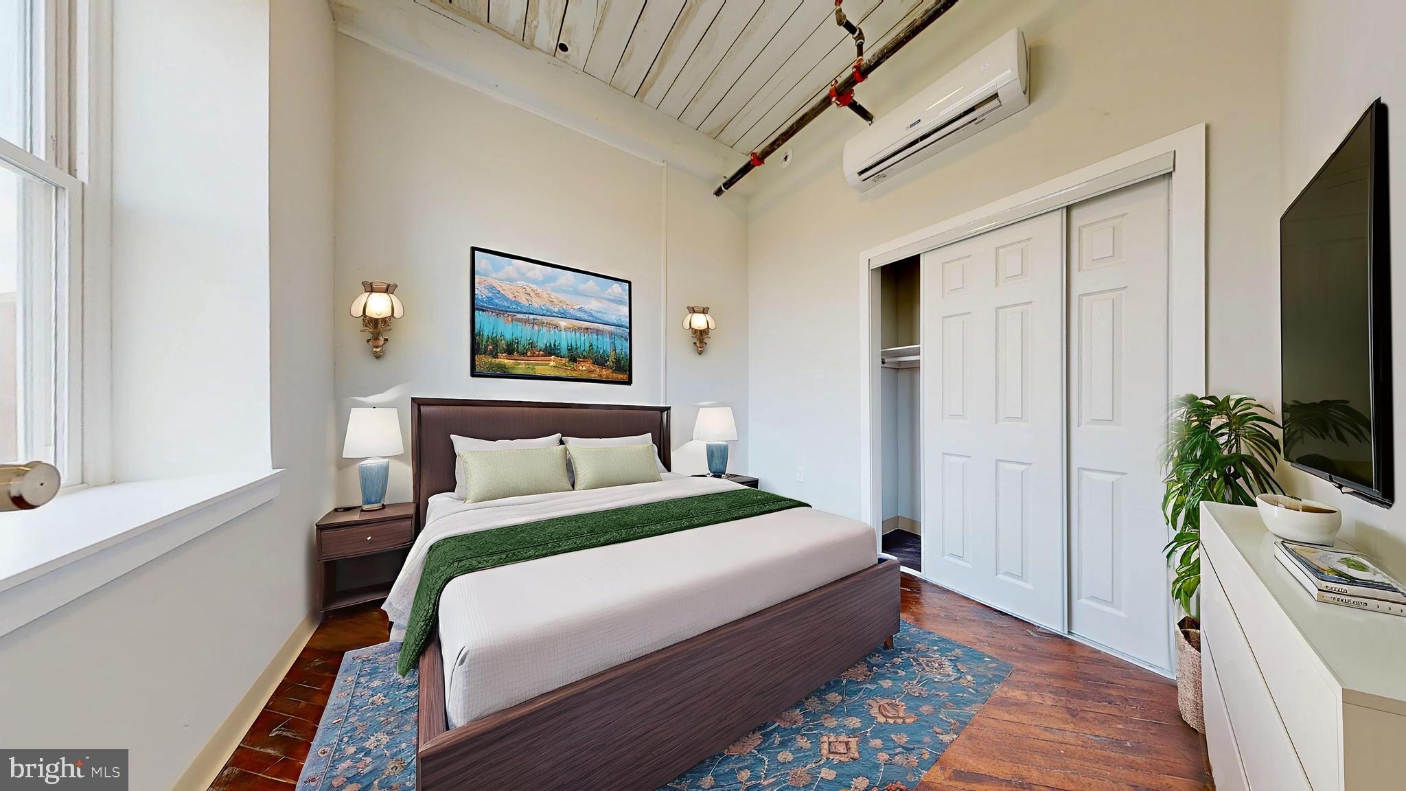 a bedroom with a bed table and a flat screen tv