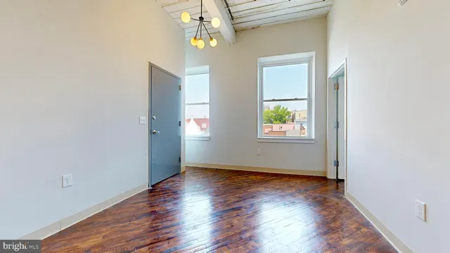 an empty room with wooden floor windows and entrance