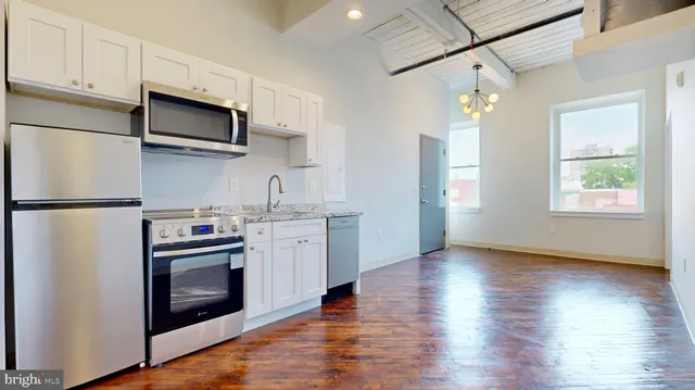 a kitchen with stainless steel appliances granite countertop a refrigerator a stove top oven a sink and dishwasher with wooden floor