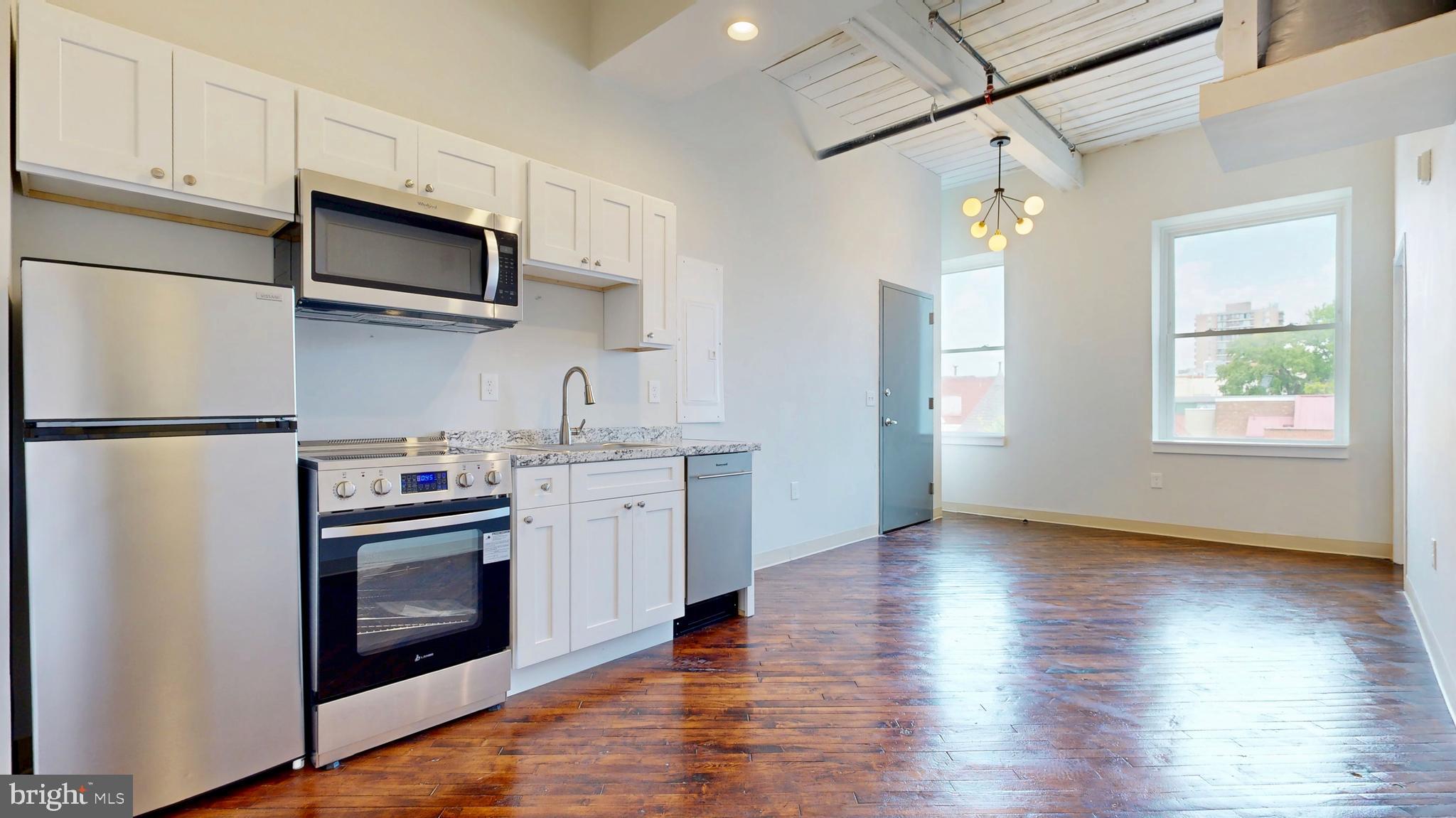 100 South 4th Street, Unit 301 Reading, PA 19602 - Photo 6 of 21 a kitchen with stainless steel appliances granite countertop a refrigerator a stove top oven a sink and dishwasher with wooden floor