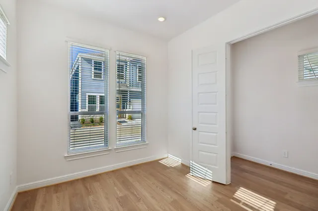 an empty room with wooden floor and windows