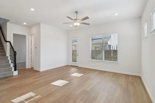 a view of an empty room with a window and wooden floor