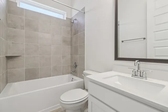 a bathroom with a granite countertop bathtub shower sink vanity mirror and toilet