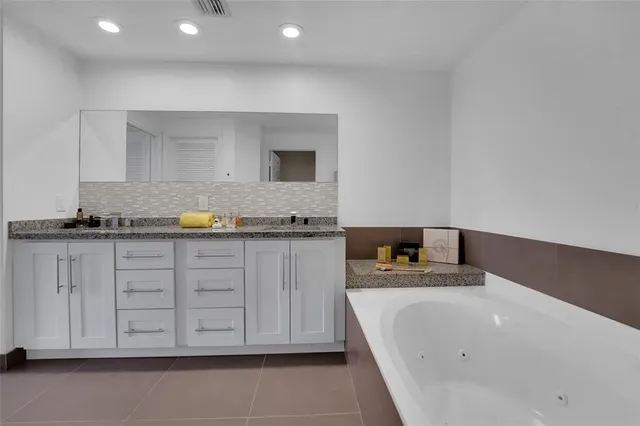 a bathroom with a granite countertop sink and a bathtub