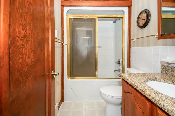 a bathroom with a granite countertop sink toilet and shower