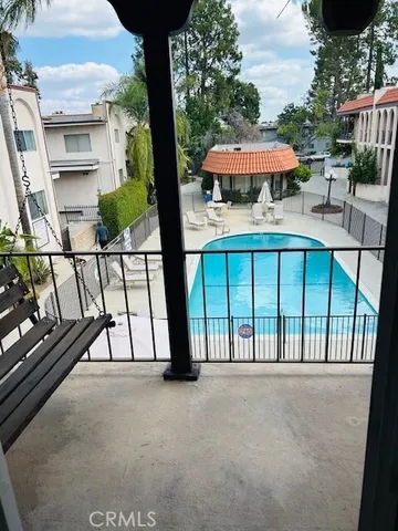 a view of a patio with a table and chairs under an umbrella with a small garden