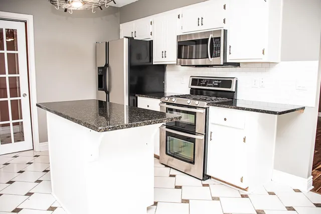 a kitchen with stainless steel appliances granite countertop a stove a microwave and a refrigerator