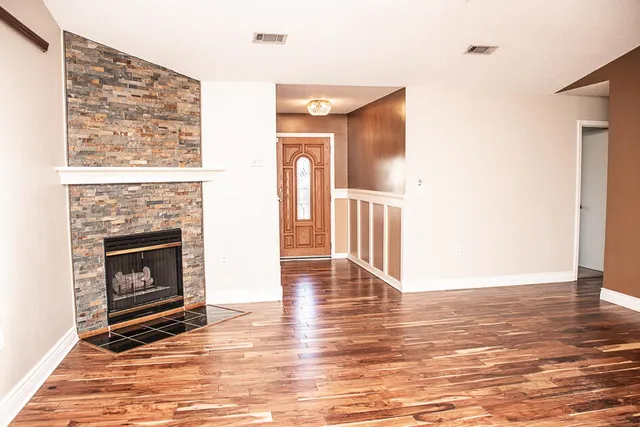 a view of a livingroom with wooden floor and a fireplace
