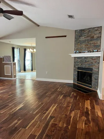 a view of an empty room with wooden floor fireplace and a window