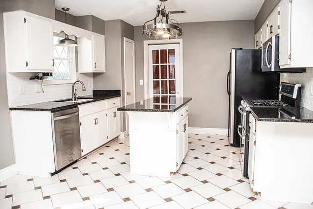 a kitchen with granite countertop a refrigerator oven a sink a stove and white countertops with wooden floor