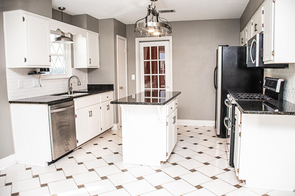 17 8th Avenue Shalimar, FL 32579 - Photo 10 of 25 a kitchen with granite countertop a refrigerator oven a sink a stove and white countertops with wooden floor