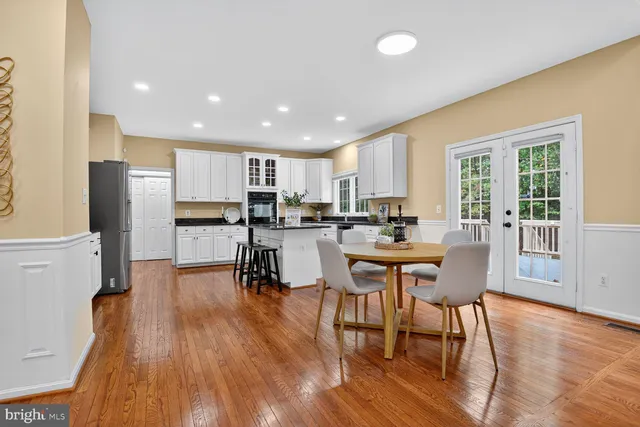a kitchen with stainless steel appliances a dining table chairs refrigerator and cabinets