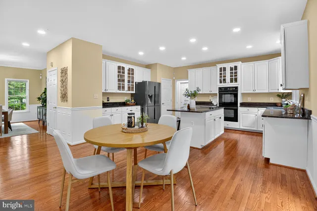 a kitchen with stainless steel appliances wooden floor dining table and chairs