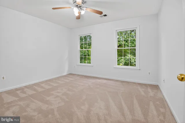 an empty room with windows and chandelier fan