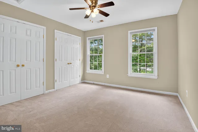 an empty room with chandelier fan and windows
