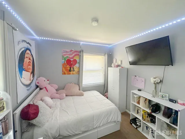 a bedroom with a bed and a flat tv screen on the dresser