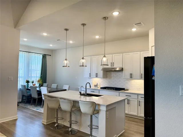 a kitchen with stainless steel appliances granite countertop a sink a stove a refrigerator and island with wooden floor