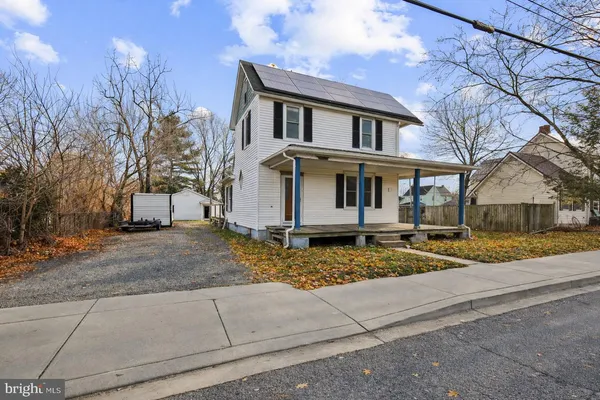 a view of a white house next to a road and yard