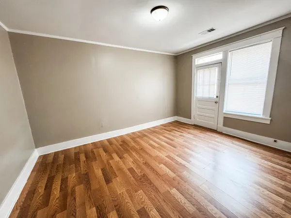 an empty room with wooden floor and windows