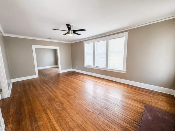 a view of an empty room with wooden floor and a window