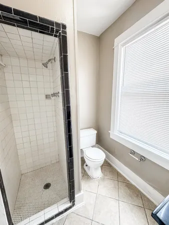 a bathroom with a shower a toilet and a window