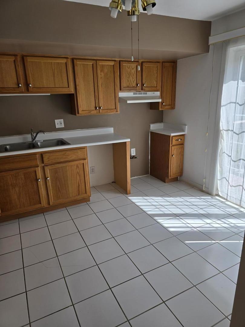 19360 Wolf Road, Unit 1 Mokena, IL 60448 - Photo 7 of 11 a kitchen with stainless steel appliances granite countertop a sink counter space cabinetry and a chandelier