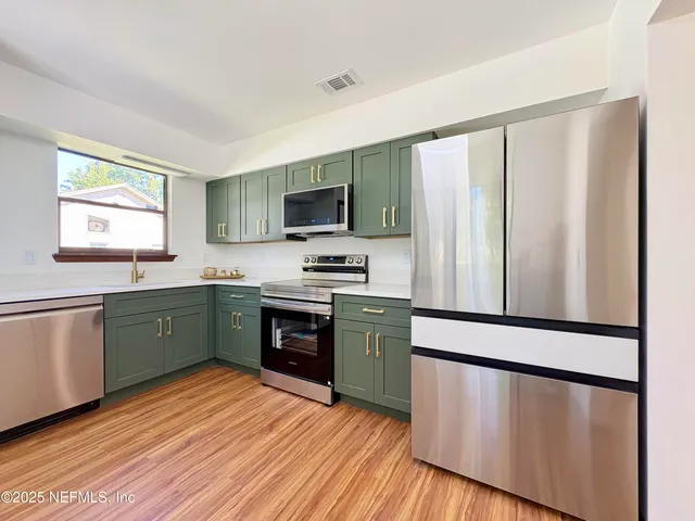 a kitchen with stainless steel appliances a refrigerator sink and microwave