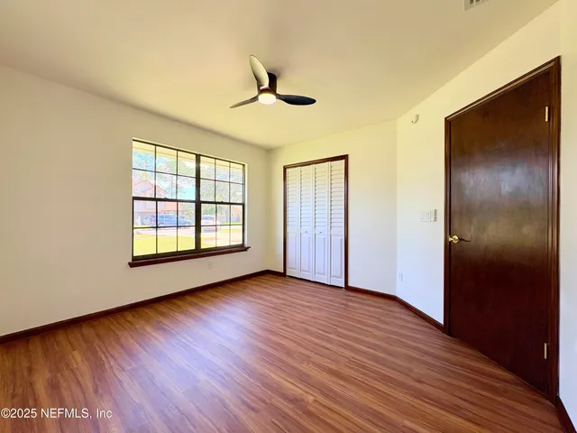 a view of an empty room with wooden floor and a window
