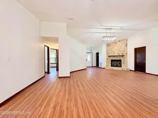 an empty room with wooden floor and fireplace