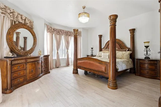 a bedroom with a bed a mirror on dresser and a wooden floor