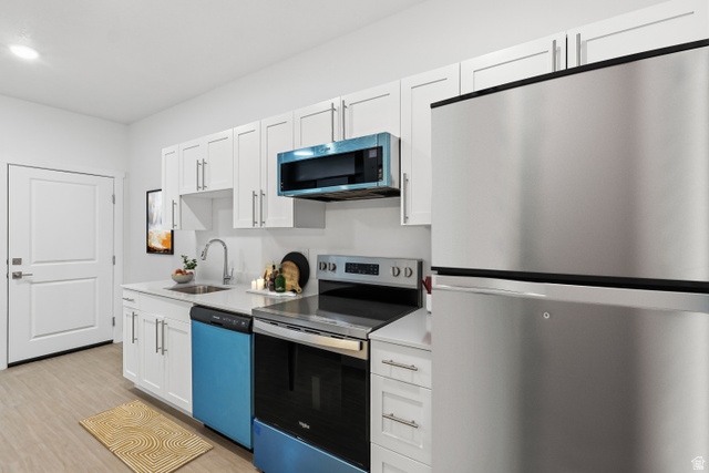 2085 North Main Street, Unit 409 Sunset, UT 84015 - Photo 1 of 10 Kitchen featuring white shaker-style cabinetry, a stainless steel refrigerator, a blue dishwasher, and a blue over-the-range microwave