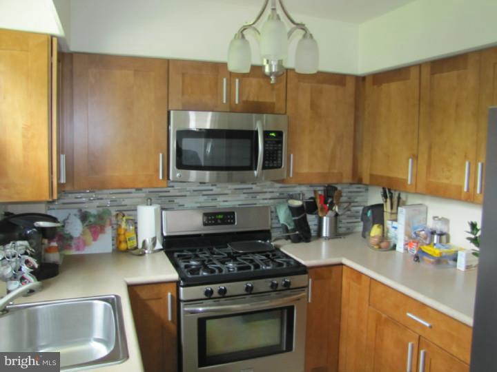 8503 Lynnewood Road Philadelphia, PA 19150 - Photo 9 of 20 a kitchen with stainless steel appliances a stove a sink a microwave a refrigerator cabinets and a counter top space