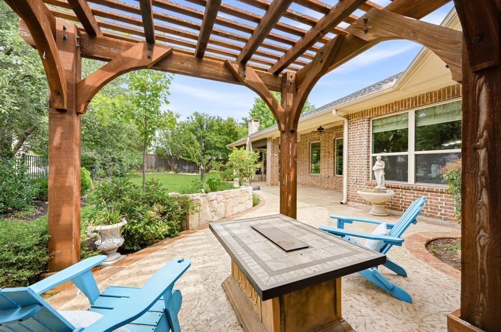 7013 Handel Colleyville, TX 76034 - Photo 31 of 37 Wood pergola featuring carved posts, stamped concrete patio, and stone retaining wall