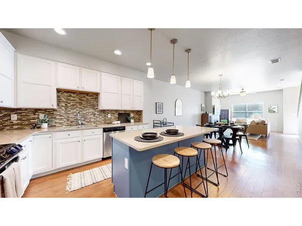 a kitchen with stainless steel appliances granite countertop a table chairs sink and cabinets