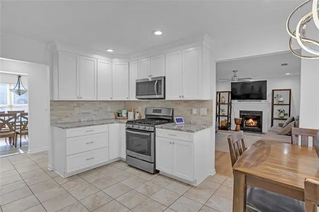 a kitchen with granite countertop a stove top oven a sink dishwasher and a microwave oven with white cabinets