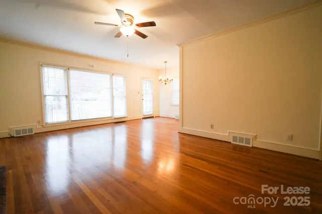 a view of an empty room with window and wooden floor