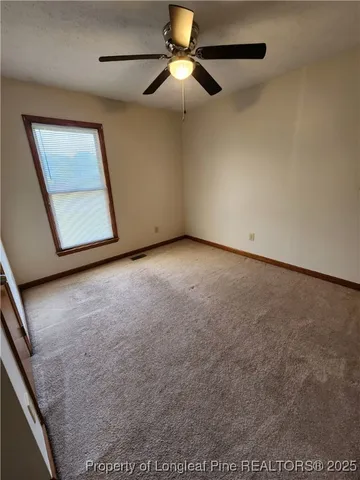 an empty room with windows and fan