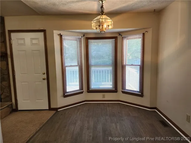 an empty room with wooden floor windows and chandelier