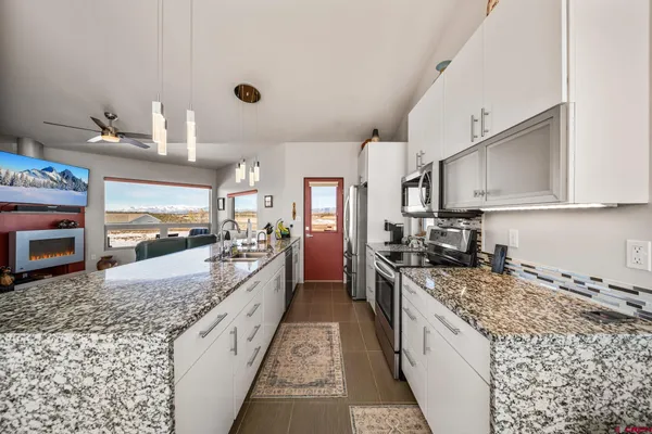 a large kitchen with granite countertop a sink and cabinets