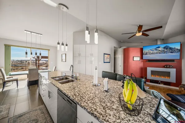 a large kitchen with kitchen island granite countertop a stove a sink dishwasher a dining table and chairs with the view of kitchen