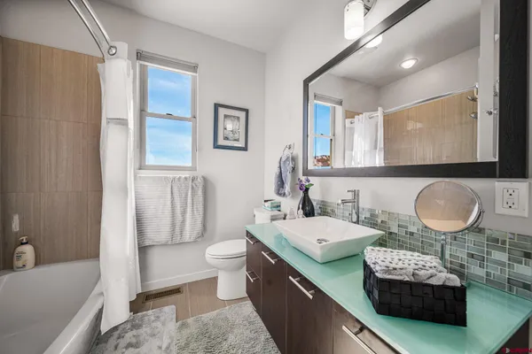 a bathroom with a granite countertop bathtub sink vanity mirror and toilet