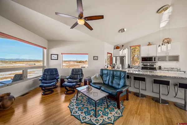 a living room with furniture kitchen view and a large window