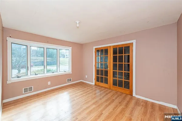 a view of an empty room with a window and wooden floor