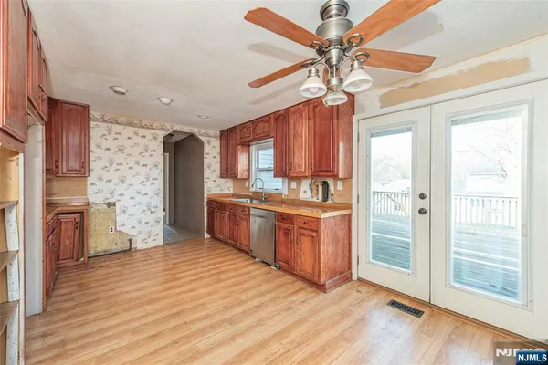 a kitchen with stainless steel appliances kitchen island granite countertop a refrigerator a sink dishwasher a stove and a dining table with wooden floor