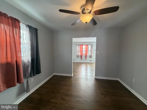 an empty room with wooden floor fan and windows